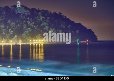 Nächtliches Panorama der Küste von Koh Rong mit beleuchtetem Pier und kleinem Boot mit grünen roten Lichtern. Hochwertige Fotos Stockfoto