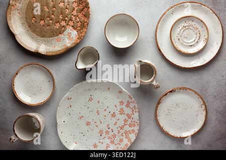 Set aus runden Keramikschalen, Tellern und Saucenbooten auf einem Vintage-grauen Hintergrund. Flache Lage, Draufsicht. Stockfoto