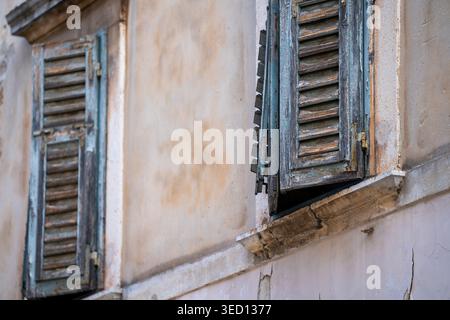 Rovinj, Kroatien - 16. August 2025: Diese eindrucksvolle Aufnahme fängt den Charme alter Architektur mit blauen Lamellen und einer gerissenen Steinfassade ein. Stockfoto