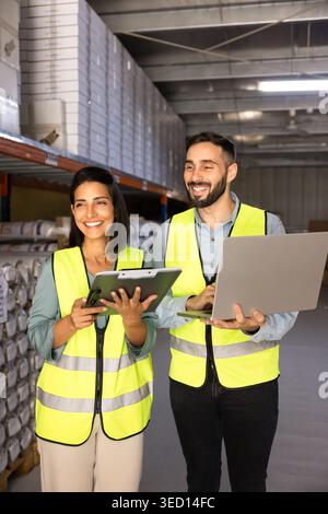 Porträt zweier lächelnder Lagerarbeiter, die im Lager zusammenarbeiten Stockfoto