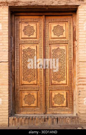Kunstvoll geschnitzte Holztür in der Shah-i-Zinda Nekropole in Samarkand mit komplizierten Blumen- und geometrischen Mustern. Ideal für Reisen, Kulturerbe und Architekturpublikationen. Stockfoto