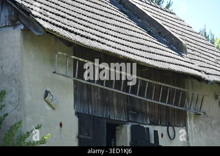 Alte Holzleiter hängt an einer rustikalen Scheunenmauer auf dem Land Stockfoto
