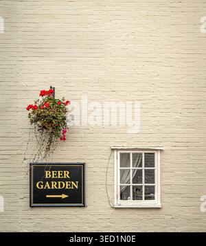 Traditionelles Beer Garden Schild an der Backsteinmauer eines britischen Publishauses mit hängendem Blumenkorb, Großbritannien Stockfoto