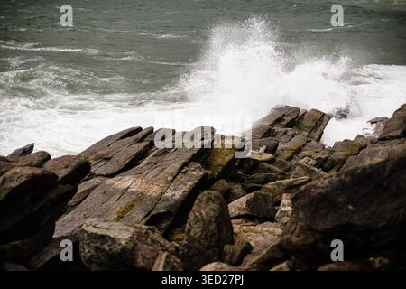 Wellen schlagen bei windigem Küstenwetter gegen Felsen Stockfoto
