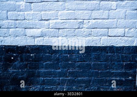 Nahaufnahme einer strukturierten Ziegelwand in kontrastierenden weißen und schwarzen Abschnitten mit selektivem Fokus. Dieses städtische architektonische Highlight Stockfoto