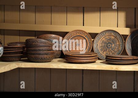 Wunderschön gefertigte Holzschüsseln und -Teller ruhen auf einem warmen Holzregal und zeigen Kunst. Stockfoto