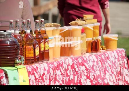 Ein lebhafter Marktstand bietet farbenfrohe Getränke und süße Leckereien in Containern. Stockfoto