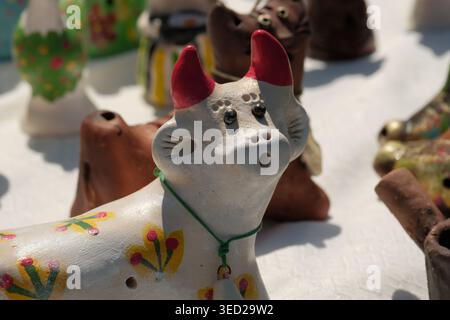 Ein charmanter Lehmhund mit hellen Blumen ziert einen belebten Marktstand. Stockfoto