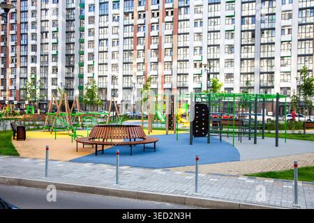 Kinderspielplatz in Wohnkomplex Hochhaus-Apartment-Gebäude-Fassade. Innenhof eines neuen mehrstöckigen Wohnviertels. Städtisches Familienleben. Kindheit in der Nachbarschaft Stockfoto