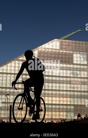 Silhouette für Radfahrer vor dem National Football Museum in Manchester, England, Großbritannien Stockfoto