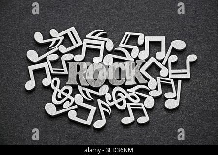 Word Rock auf einem Stapel von schwarz-weißen Holzbuchstaben und Musiknoten Stockfoto