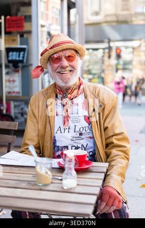 Stilvoller älterer Mann, der vor einem Café im Stadtzentrum von Manchester sitzt, England, Großbritannien Stockfoto