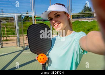 Frau, die Selfie macht, nachdem sie Pickleball auf dem Platz gespielt hat Stockfoto