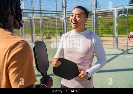 Verschiedene Männer genießen das Pickleball-Spiel auf dem Platz Stockfoto