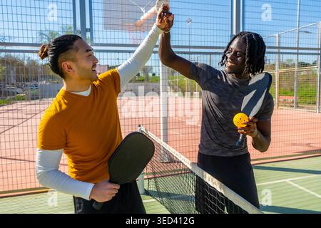 Verschiedene Freunde geben nach dem Pickleball-Spiel High 5 Stockfoto