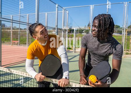 Verschiedene Freunde lachen und genießen Pickleball auf dem Platz Stockfoto