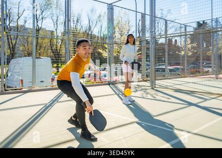 Junge Freunde, die auf dem Platz im Freien pickleball spielen Stockfoto