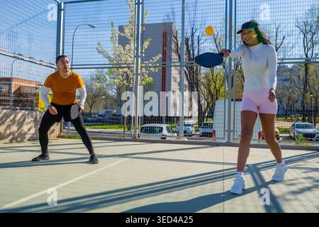 Verschiedene junge Paare spielen Pickleball auf dem Platz im Freien Stockfoto