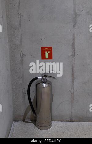 Brandschutzausrüstung mit Feuerlöscher und Schild an Industriebonwand, Notfallvorsorgekonzept Stockfoto