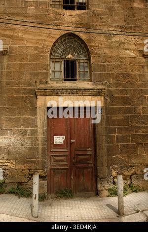Traditionelle libanesische Architektur mit einer roten Holztür und einem Bogenfenster in einem historischen Steingebäude in Beirut, Libanon. Stockfoto
