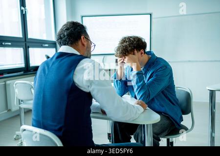 Lehrer, der sich um einen schwer wiegenden Schüler kümmert. Junge, der sich einem Lehrer anvertraut. Stockfoto