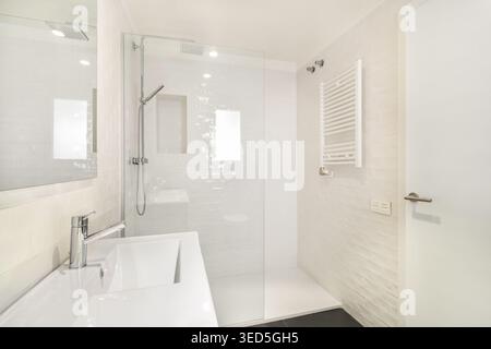 Modernes Bad mit elegantem Design. Mit Glasdusche, weißen Fliesen und minimalistischem Waschbecken. Helle und saubere Atmosphäre. Stockfoto