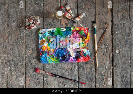 Palette, Tuben mit Ölfarbe und Künstlerpinsel auf hölzernem Hintergrund Stockfoto