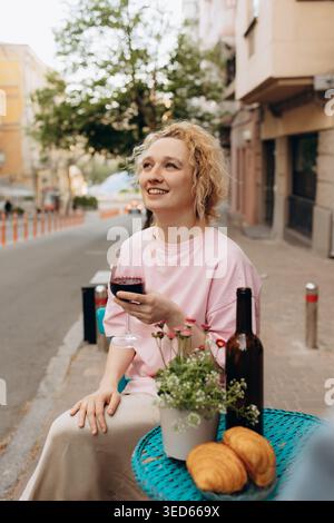Eine junge Frau trinkt Rotwein im Café im Freien Stockfoto