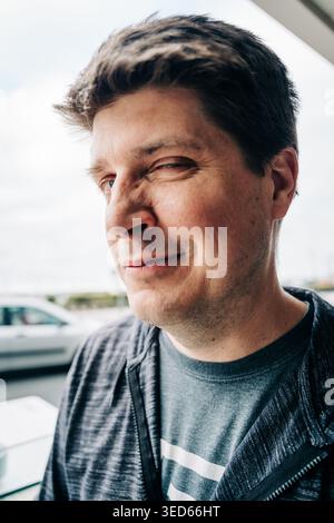 Ein verspielter Mann, der in einem lässigen Nahaufnahme-Porträt im Freien zuzwinkert Stockfoto