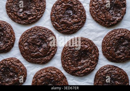 Blick von oben auf viele Schokoladen-Brownie-Kekse auf Pergamentpapier. Stockfoto