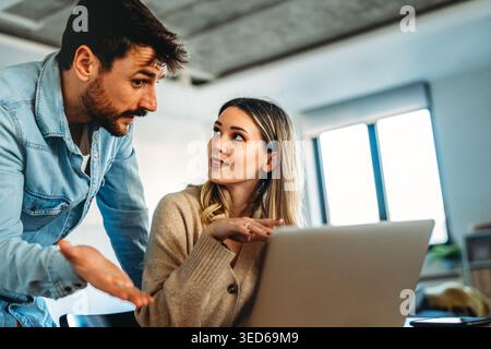 Mann und Frau, die per Fernzugriff mit einem Laptop arbeiten. Männliche Freiberufler arbeiten zusammen. Digitaler Nomade Stockfoto