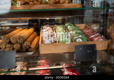 Bunte Macarons und Süßigkeiten in einer Glasvitrine eines modernen Cafés. Konzept von französischem Gourmet-Gebäck, Süßwaren und luxuriösen Dessertspeisen Stockfoto