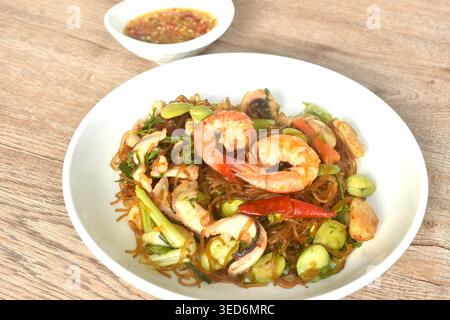 Gebratene Glasnudeln mit drei stinkenden Gemüsesorten und Garnelenpaaren Tintenfischen auf Teller mit würziger Chili-Sauce Stockfoto