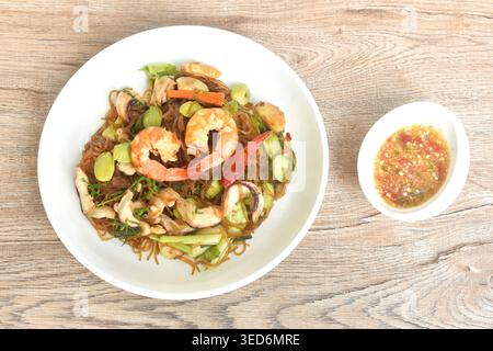 Gebratene Glasnudeln mit drei stinkenden Gemüsesorten und Garnelenpaaren Tintenfischen auf Teller mit würziger Chili-Sauce Stockfoto