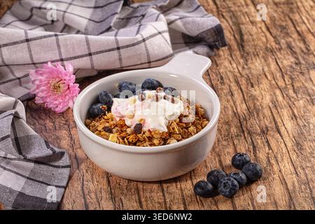 Köstlicher Frühstückssnack mit knusprigem Müsli, cremigem Joghurt und saftigen Heidelbeeren. Garniert mit Schokoladenkugeln, weißen Schokoladenstückchen Stockfoto