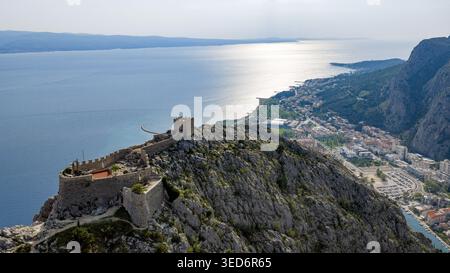 Blick aus der Vogelperspektive auf die historische Festung Starigrad auf einem zerklüfteten Bergkamm mit Blick auf die Küstenstadt und die blaue Adria in Omis, Spli Stockfoto