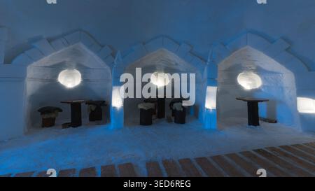 Eine beleuchtete Eishöhle in Zermatt, Schweiz, mit drei gebogenen Nischen und Tischen, die in ein kühles, ätherisches blaues Licht getaucht sind. Der Architec Stockfoto