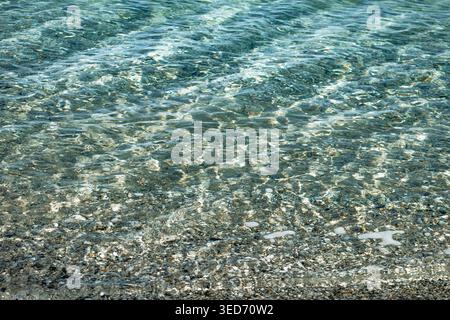 Kristallklares, seichtes mediterranes Wasser in Plage d Argent auf der Ile de Porquerolles mit Kieselboden und Sonnenlichtreflexionen Stockfoto