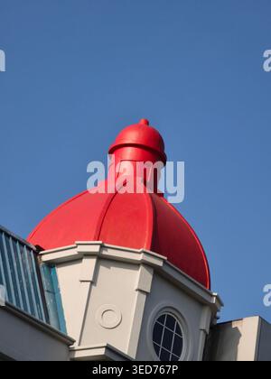 Die rote Kuppel eines beeindruckenden modernen Gebäudes, das unter klarem blauem Himmel steht, zeigt klare architektonische Linien und elegantes Design im europäischen Stil Stockfoto