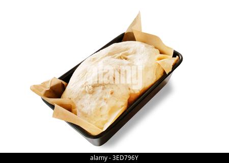 Hausgemachter Brotteig in einer mit Backpapier ausgelegten Kastenform, bereit zum Backen im Ofen. Bild auf weißem Hintergrund ausschneiden. Stockfoto