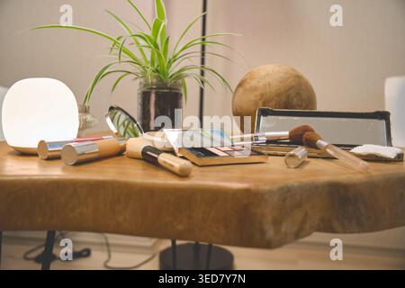 Make-up-Produkte, Pinsel und Pflanzen, die auf einem Kosmetiktisch angeordnet sind, schaffen eine Schönheitsszene Stockfoto