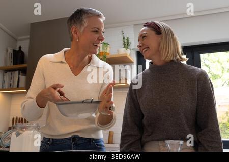 Ältere und Erwachsene weibliche Familienmitglieder sieben Mehl mit Metallsieb über der Rührschüssel an der Theke Stockfoto