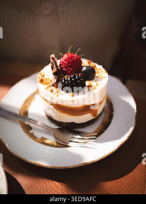 Mehrschichtiger Karamell-Mousse-Kuchen mit frischen Beeren und Schokoladenlocken auf Vintage-Teller im Café Ott and Matilda in Estland Stockfoto