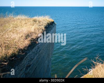 Kalksteinklippe mit trockenem Gras mit Blick auf die Ostsee in Paldiski, Estland, an einem klaren Frühlingstag Stockfoto