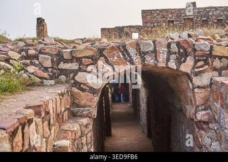 Alter Steinbogen bildet einen schmalen Tunnelgang in historischen Festungsruinen. Die verwitterte Mauerkonstruktion zeigt unregelmäßige rötlich-braune Steine Stockfoto