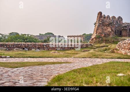 Ein malerischer Blick auf alte Steinruinen und Befestigungen mit einem Kopfsteinpflasterweg, der sich durch grasbewachsenes Gelände schlängelt. Die verwitterten Ziegel- und Steinmauern. Stockfoto