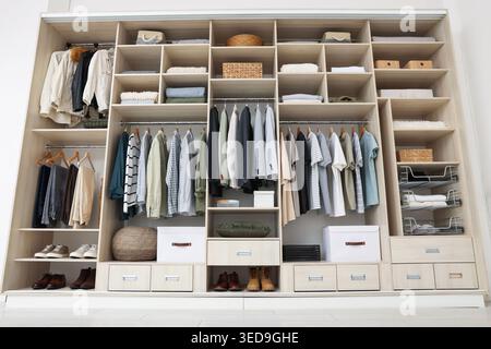 Kleiderschrank mit verschiedenen stilvollen Kleidungsstücken, Accessoires, Schuhen und Haushaltsgegenständen im Innenbereich, geringer Blickwinkel Stockfoto