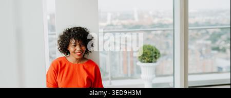 Porträt einer schönen afroamerikanischen Frau, die am Fenster steht. Stockfoto