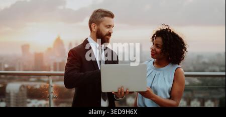 Zwei Geschäftsleute unterhalten sich auf der Dachterrasse des modernen Büros Stockfoto
