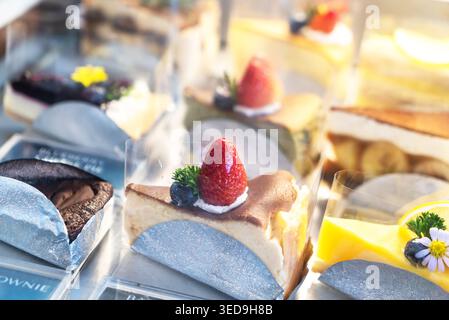 Eine lebendige Auswahl an Käsekuchen-Scheiben mit frischen Früchten wie Erdbeeren und Heidelbeeren, perfekt für Feiern, Desserttische, Stockfoto